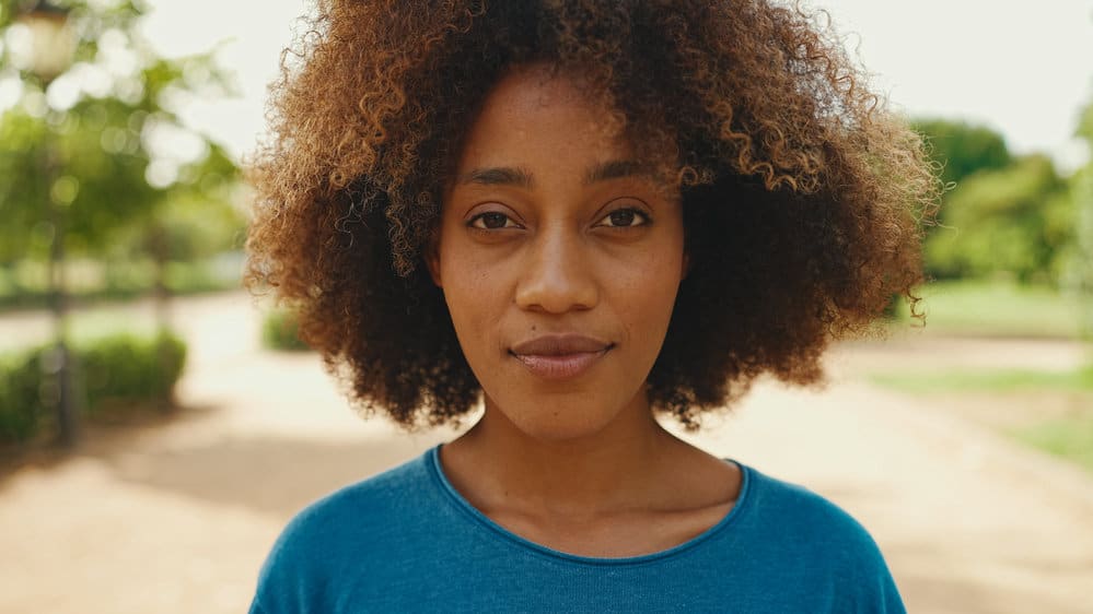 A black female that's worried about future hair thinning due to slow hair growth and dry hair from a risky hair care routine.