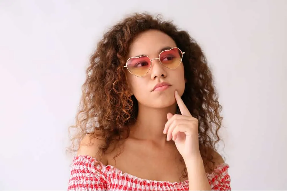 What Is 3B Hair? How To Take Care of It, Styles, and Products 2 A thoughtful African-American female with a coarser hair texture used a blow dryer style dry and style her wet hair.