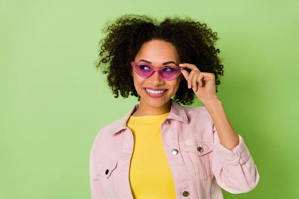 A black girl with stretchy hair uses the Curly Girl hair care routine to make her hair shine and more moisture-filled.