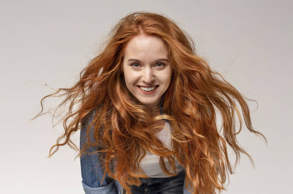 A cute red head with 2B hair strands using the Curly Girl method for a proper hair care routine for her wavy strands.