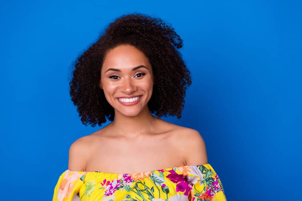 A beautiful young with revived curls after having straight hair from a keratin express treatment on her color-treated hair strands.