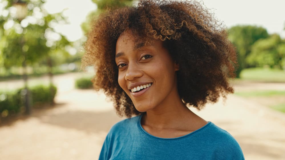 Light-skinned black girl with porous hair styled with a hair dryer and olive oil to make her hair shiny.