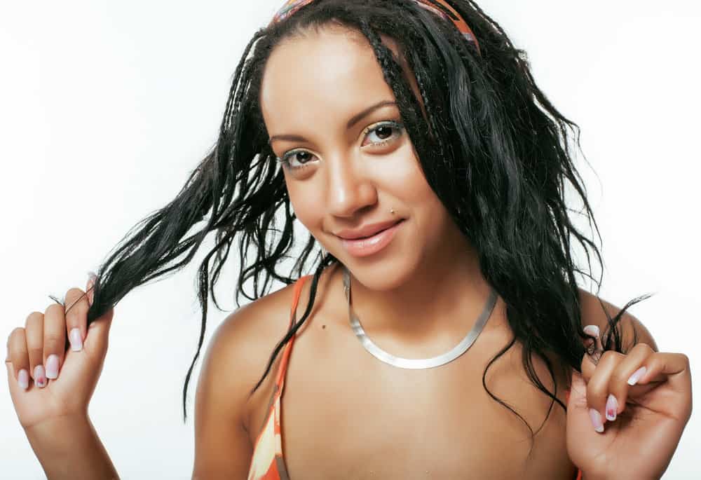 Young black girl with thinning hair follicles and female pattern hair loss due to wearing tight braids on her fine hair.