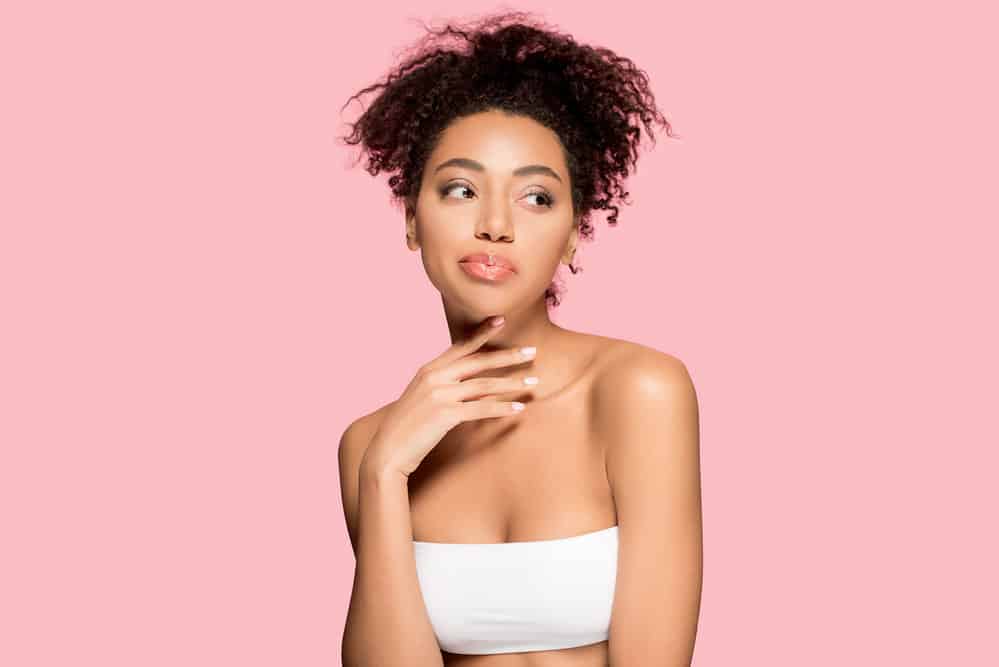 A cute African American female with completely dry natural curls after using a hair dryer following a shower.