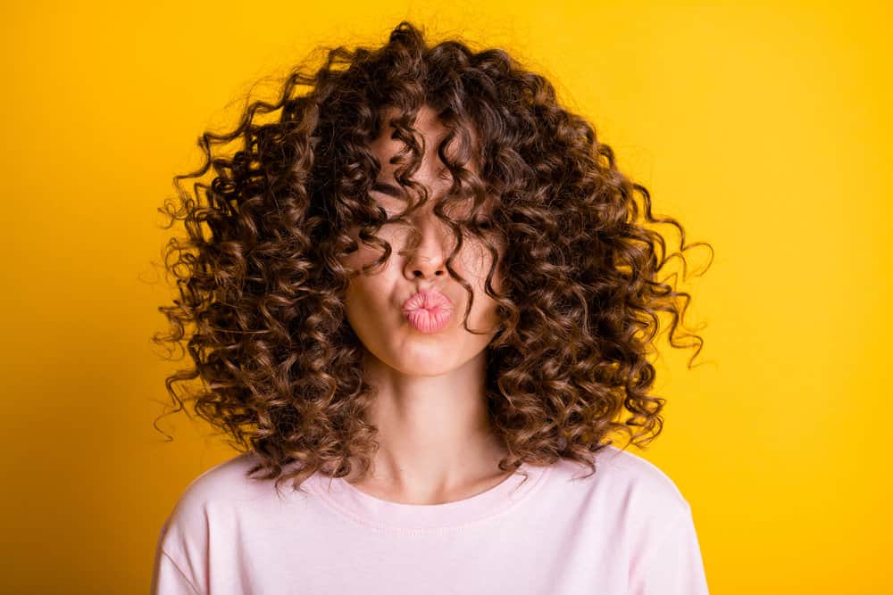 A woman that had straight permed hair is now wearing a beautiful curly hairstyle after using moisture-rich shampoo.