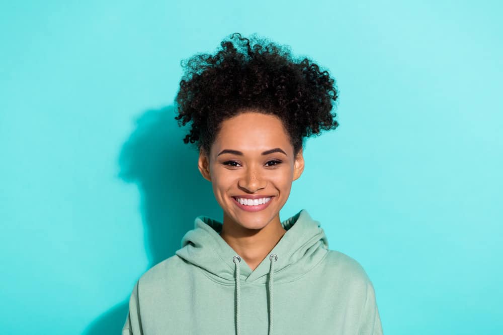 A young black lady with chemically altered hair used a scalp conditioner to relieve her itchy scalp. 