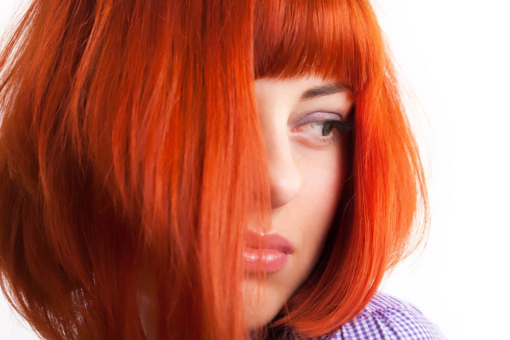 A young woman preparing for a Splat hair dye review dyeing her dark brown hair with Manic Panic red dye.