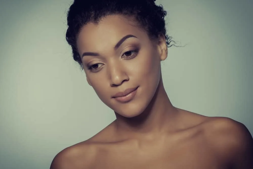 How to Stop Hair From Tangling at the Nape of Your Neck 10 A happy young black woman wearing hair extensions shows a slight smile after using argan oil for tangling hair.