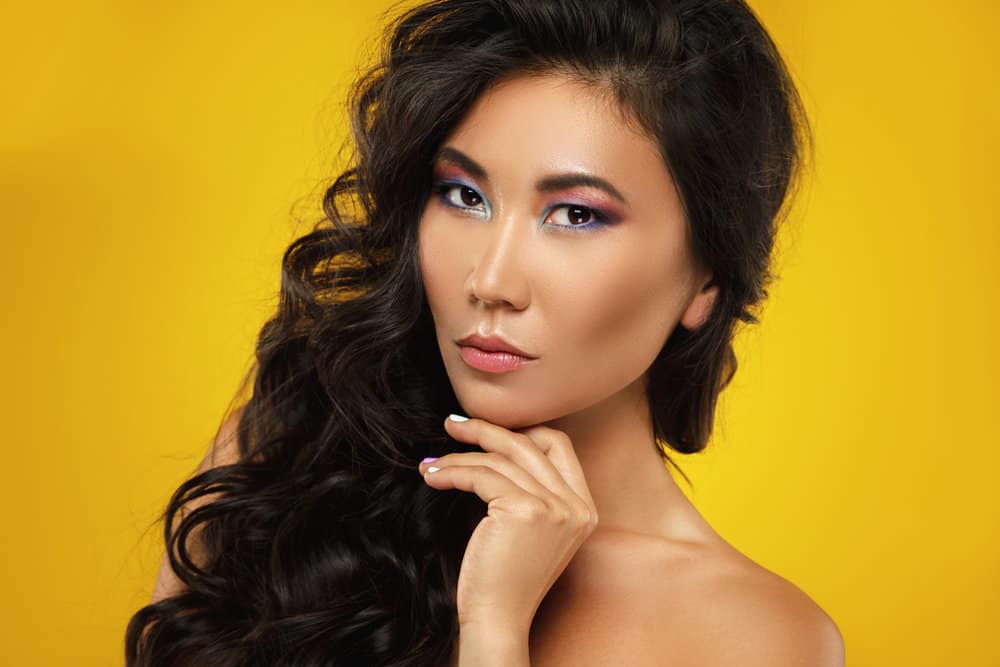A young Asian girl with long wavy hair wearing a classic Asian hairstyle with colorful eye makeup.