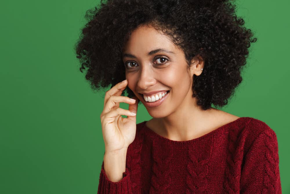 A black female with healthy hair used a protein treatment on her dry hair strands to counteract moisture overload.