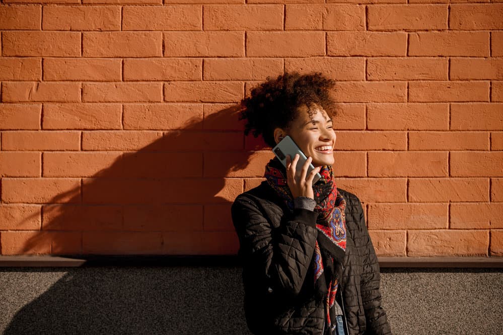 A young girl talking on the phone to a friend has an 'S' shaped curl pattern on her type 3 low porosity hair strands.