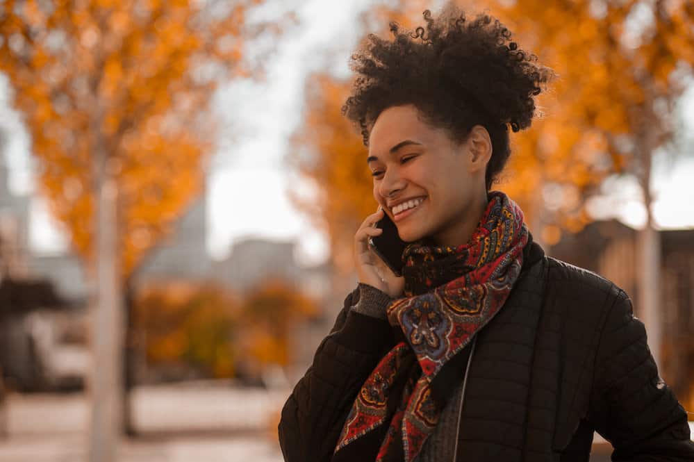 A joyful young female with kinky hair is a new member of the natural hair community with beautiful frizz-free curls.