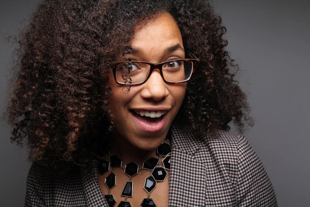 A cute African American female takes a biotin supplement to ensure she gets enough biotin to prevent hair loss.