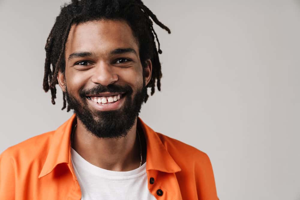 A young black guy with 4C natural hair with, a well-groomed appearance, dreadlocks, and wild beard growth.