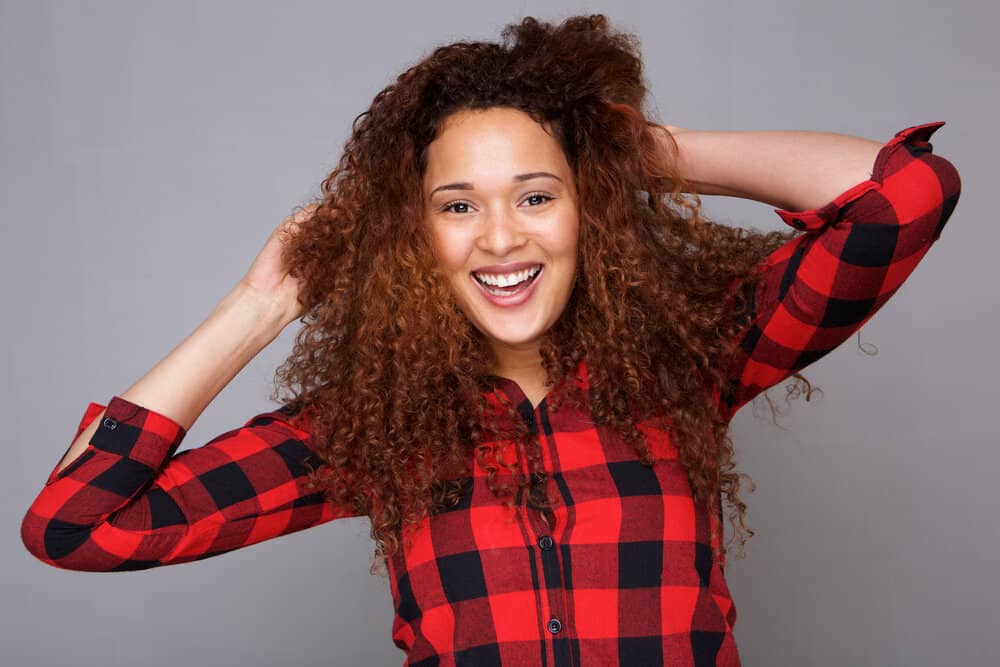 A young Hispanic woman wearing a mixture of semi-permanent hair colors on her type 3 damaged hair strands.