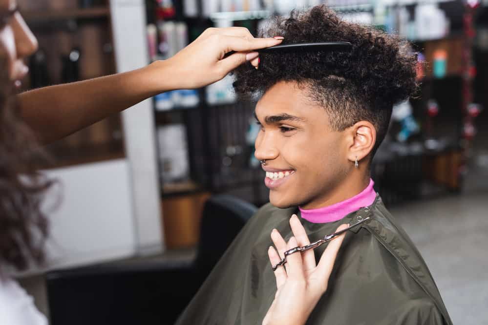 A young black girl cutting hair in a commercial salon that provides free and cheap haircuts to veterans and the elderly.