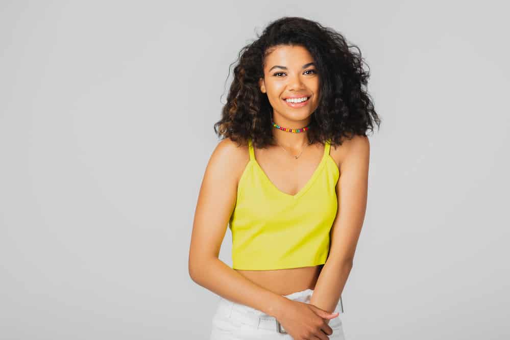 African American female with curly hair strands washed her dirty hair with a moisturizing shampoo and styled it.