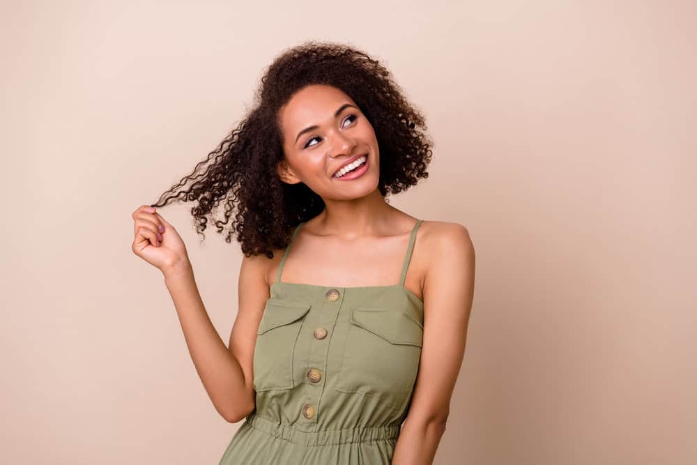 A beautiful female with natural curls used a conditioner specifically formulated for curly girls to moisturize her curls.