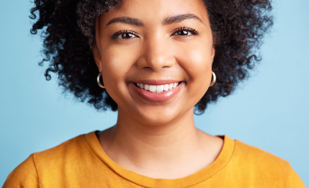 A female with curly hair follicles styled with natural hair gels and oils to prevent hair thinning and prolonged hair fall.