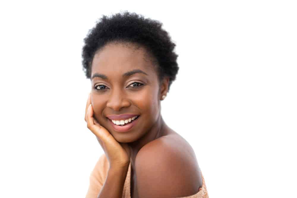 Side photo of dark-skinned black woman with a kinky hair type wearing an off-the-shoulder shirt.