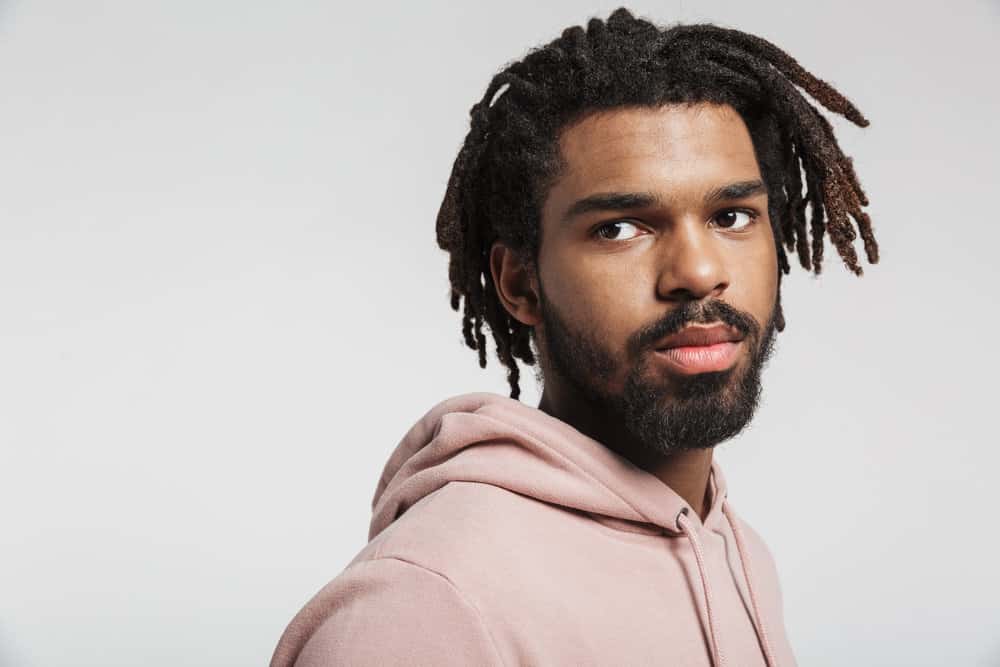 A black man with mature dreads started with comb coils and has been maintaining his locs with palm rolls.