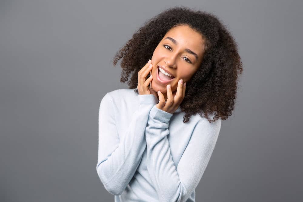 A black female with highly sensitive skin has naturally curly hair strands styled with aloe vera gel and coconut oil.