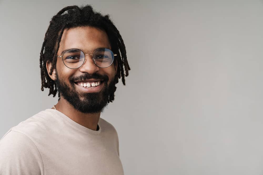 A guy with thick hair wearing thriving locs that have experienced healthy growth since being treated with essential oil.