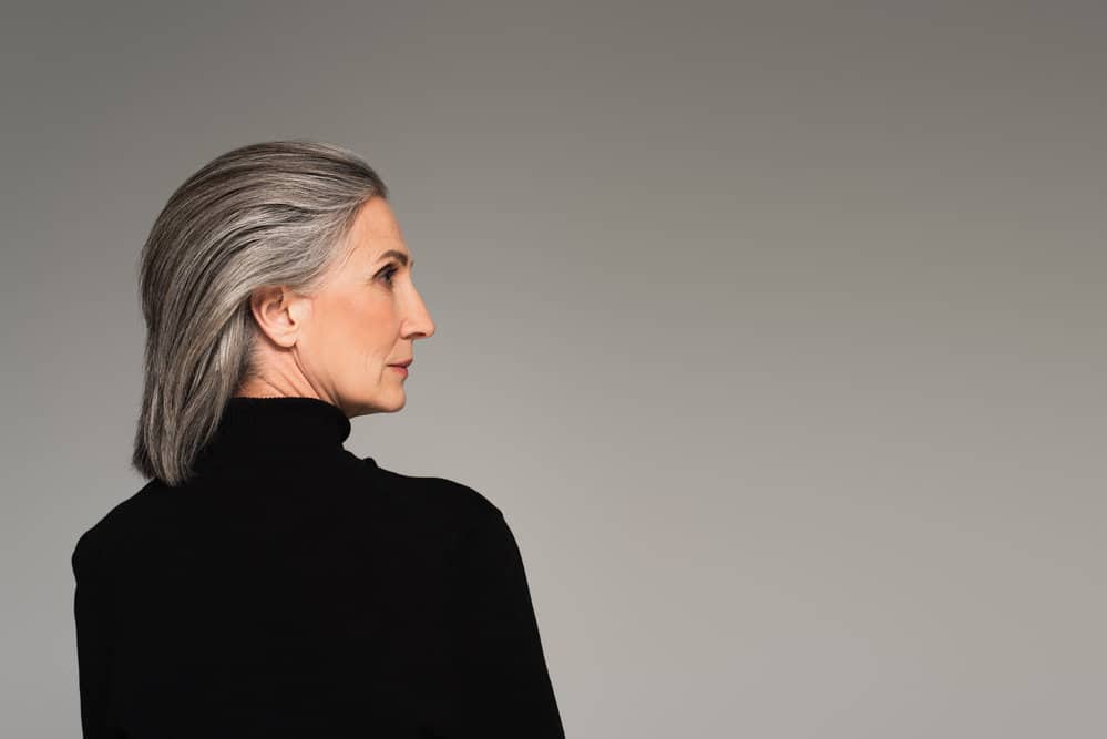 An older female with beautiful graying hair that's blended with her natural long hair and darker tone natural color.
