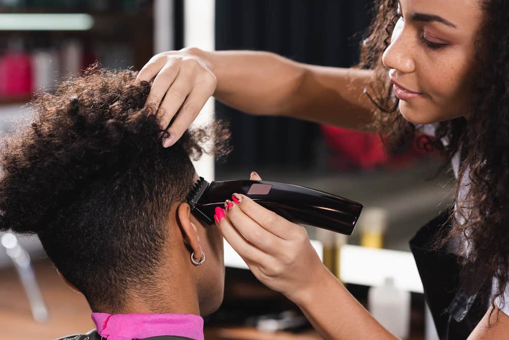 A young black guy that hair modeling at a salon than offering free haircuts at a local barbershop.