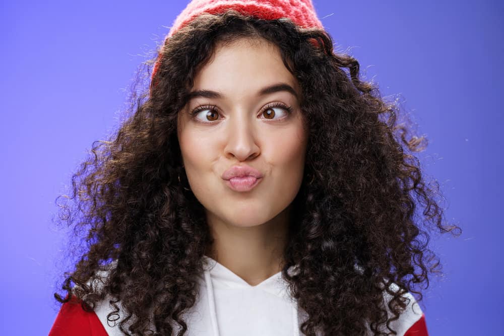 White lady with curly hair strands suffering from hair fall following a perm treatment on her naturally straight hair.