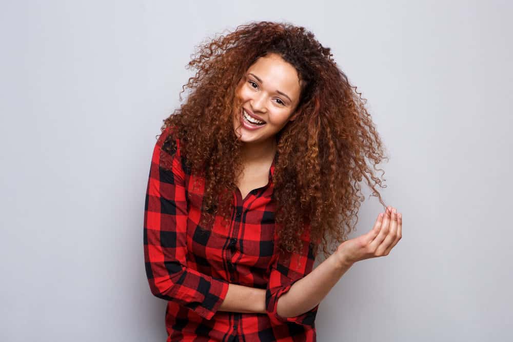 A smart young lady with dark brown curly hair dyed with semi-permanent hair dye.