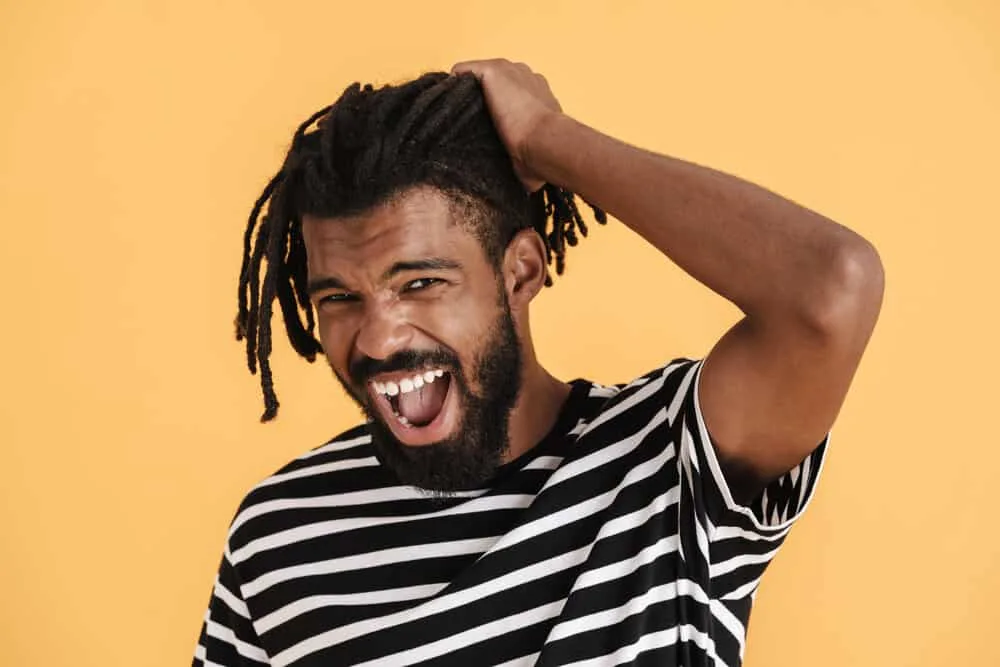 How Often Should I Wash My Locs? What if I Workout? 3 A black guy with healthy dreads is experiencing matted hair clumped together with hair flakes, like dandruff.
