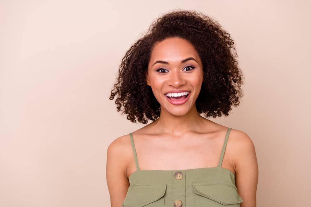 A pretty female with a dark brown natural hair color dyed with Arctic Fox hair dye on curly virgin hair strands.