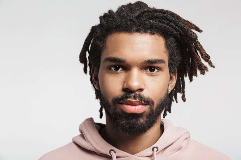 A young African man with traditional locs that are a mid-neck hair length on a 4B hair texture / medium hair density.