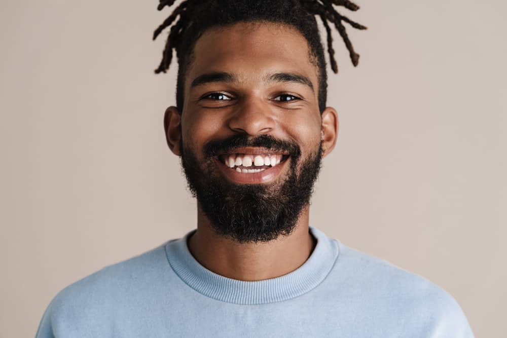 African American man with starter locs used natural hair care products, like coconut oil, to keep his hair moisturized.