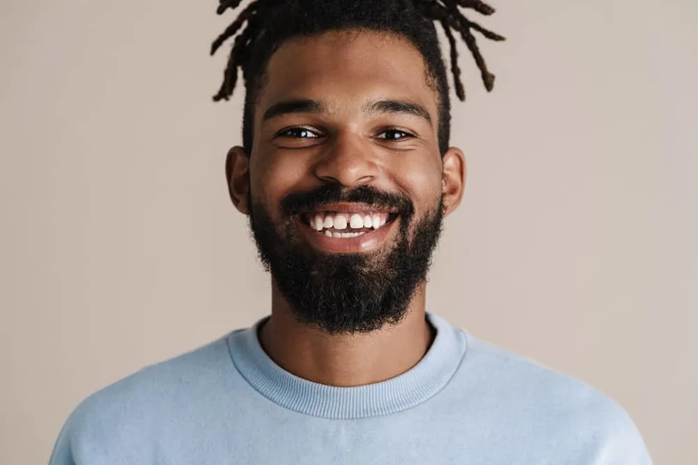 How Often Should You Oil Your Locs? Should You Oil Them Daily? 1 African American man with starter locs used natural hair care products, like coconut oil, to keep his hair moisturized.