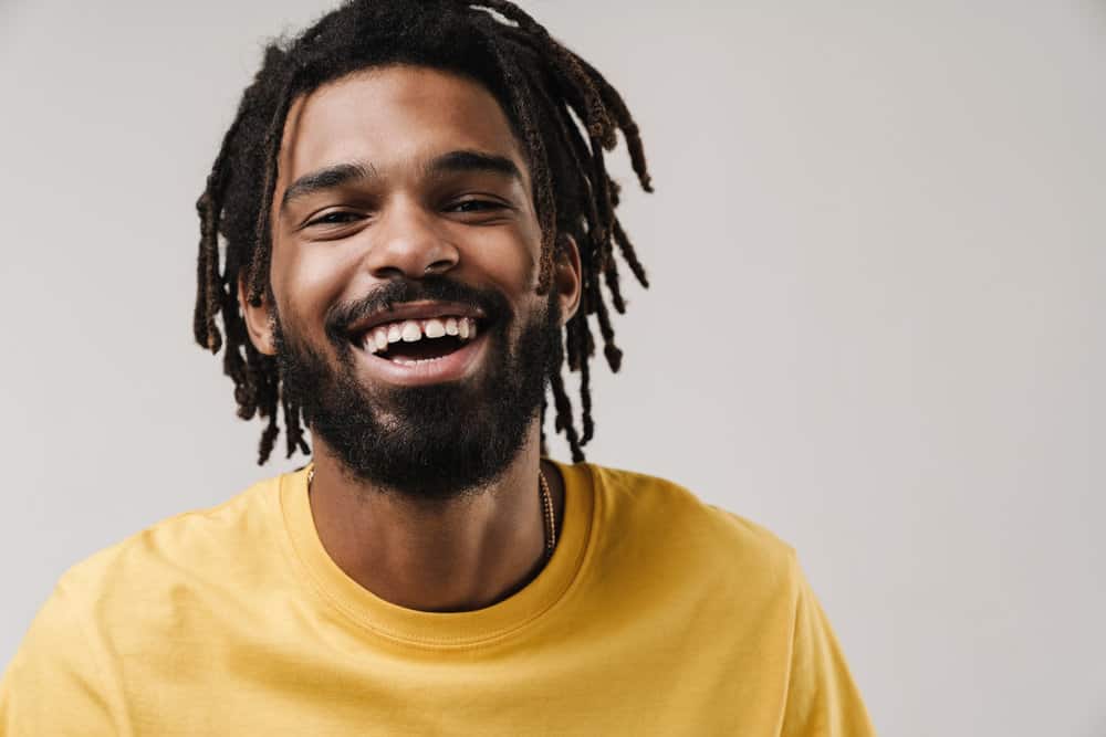 A young black guy wearing semi-freeform dreads with loose hair since his dreads were formed organically.