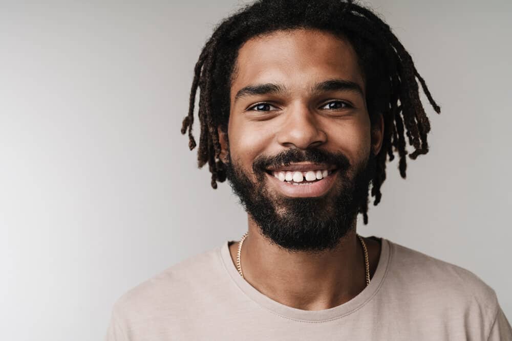 A young black man with healthy locs on 4B natural hair styled with tea tree oil, olive oil, and aloe vera juice.