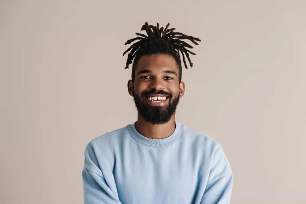 How Often Should You Oil Your Locs? Should You Oil Them Daily? 4 A black man with baby locs uses emollient oil and avocado oil to moisturize dry locs to keep his locs healthy.