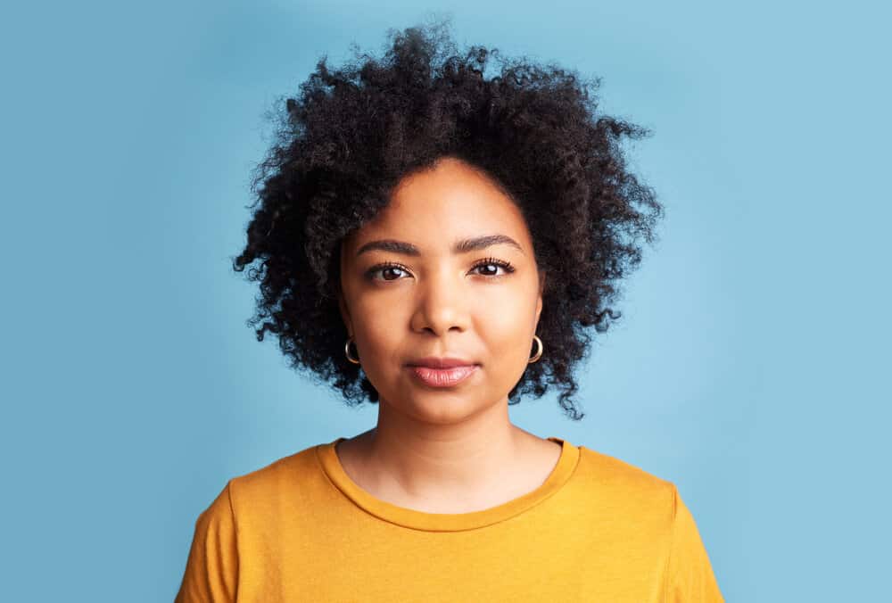 A light-skinned African female with naturally curly hair styled with essential oils and coconut oil leave-in conditioner.