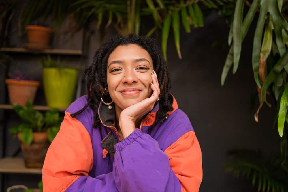 African American female with braided hair and loc extensions starting her dreadlock journey with two-strand twists.