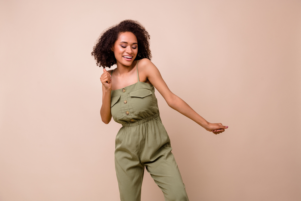 An adorable woman wearing a curly hairdo with a fairly vibrant new hair color that smells great.