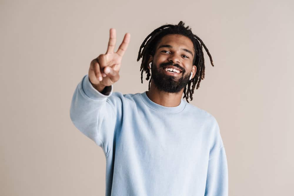 African American male that believes moisturized locs begins with using rose water in a spray bottle to spray his dreads.