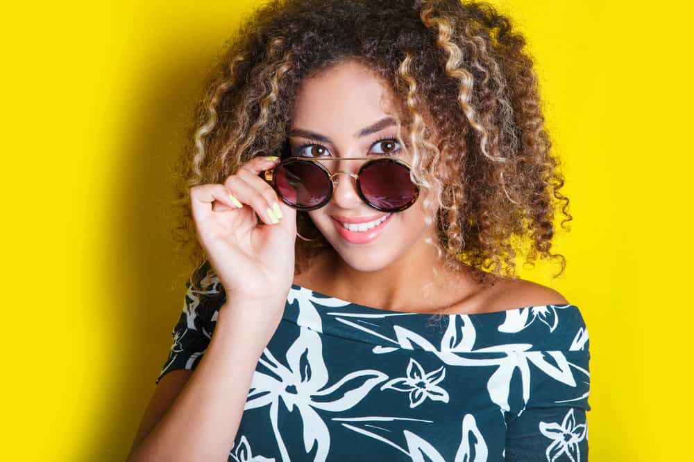 A mixed-race black girl with color-treated hair strands on subtle highlights on traditionally dark hair.