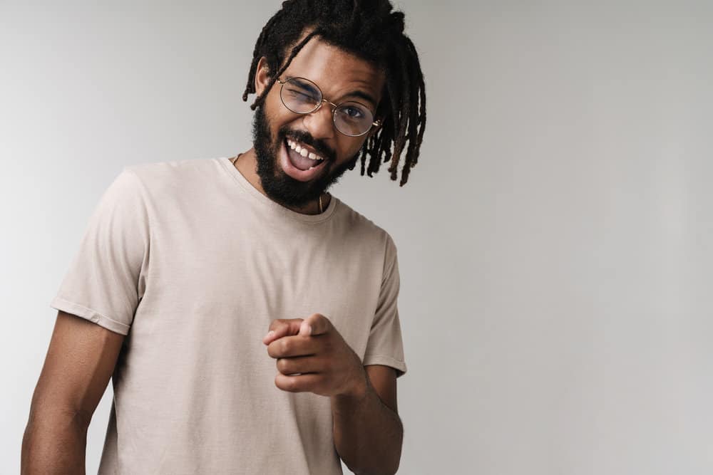 A 30-year-old African male with should-length hair growth on his mature dreadlocks wearing a beige t-shirt.