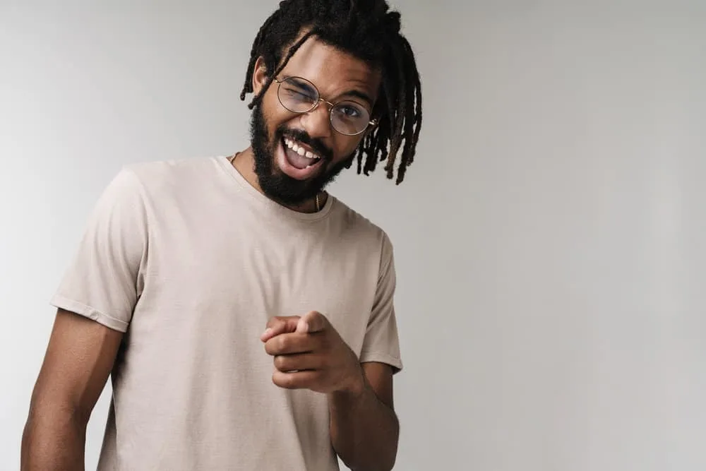 How to Moisturize Starter Locs and What to Use to Hydrate Locs 5 A 30-year-old African male with should-length hair growth on his mature dreadlocks wearing a beige t-shirt.