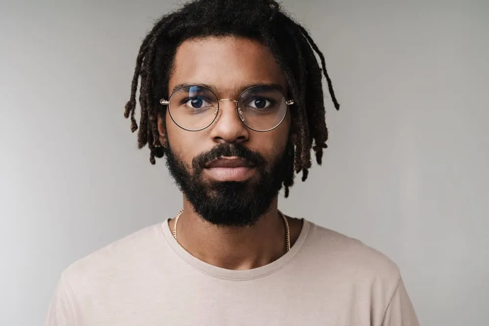 How to Moisturize Starter Locs and What to Use to Hydrate Locs 9 A confident young black man with dreads in the starter loc phase keeps his scalp moisturized with distilled water.