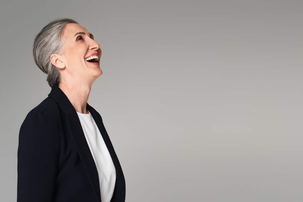 A cute white lady wearing natural gray strands with gray roots and white hairs that naturally fits her face shape.