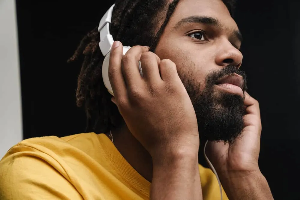 How to Maintain Semi-Freeform Locs: Step-By-Step DIY Guide 6 African guy with freeform dreads listening to the latest Cardi B album on his Beats headphones.