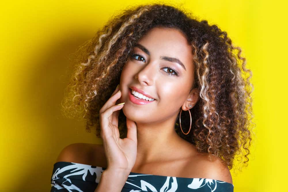 A light-skinned black female with an ombre hair color technique on her beautiful 3B natural curls.